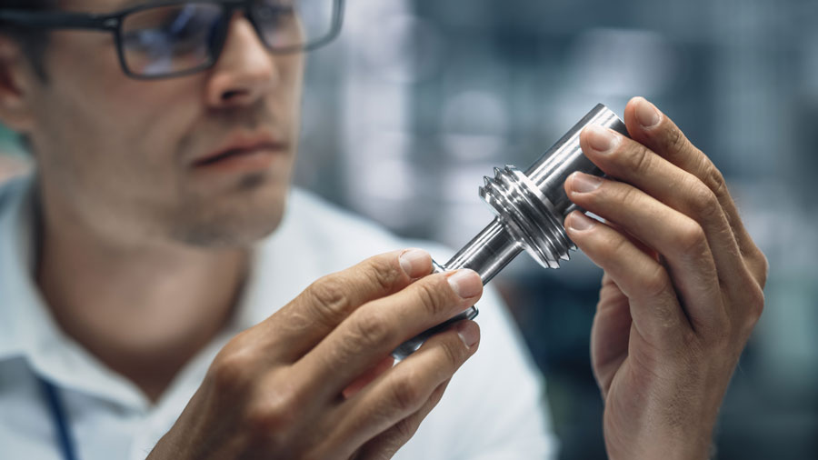 Engineer inspecting precision CNC turned metal component